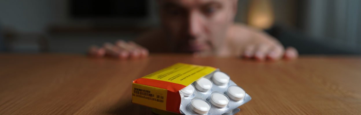 Мужчина смотрит на упаковку таблеток